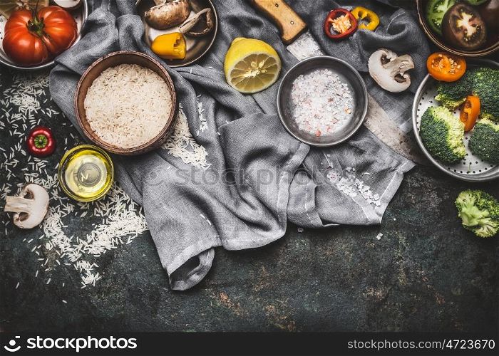 Vegetarian cooking ingredients with lemon, rice and vegetables on dark rustic background, top view, border. Healthy or diet food concept