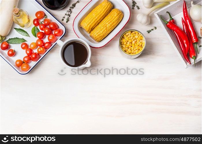 Vegetarian corn soup preparation with various corn, broth and cooking ingredients on white wooden background, top view, border. Healthy food concept