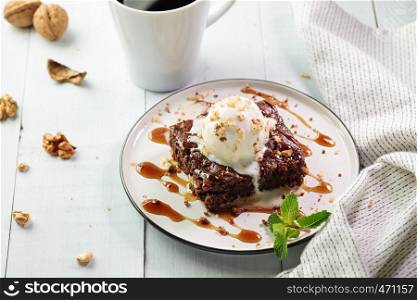 Vegetarian dessert - brownie with ice cream on the top served on white plate with cup of black coffee