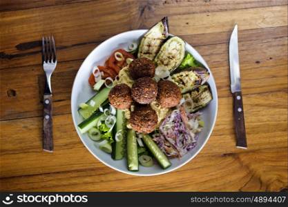 Vegetarian falafels and vegetables in bowl on white wood &#xA;