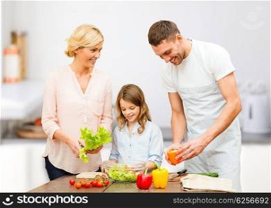 vegetarian food, culinary, happiness and people concept - happy family cooking vegetable salad for dinner in home kitchen