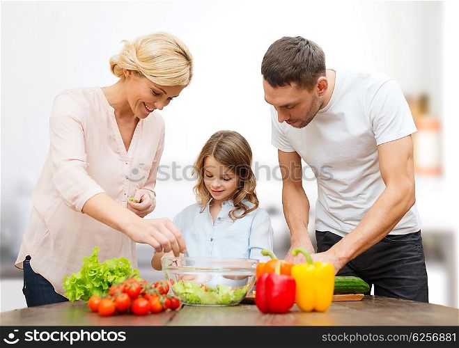 vegetarian food, culinary, happiness and people concept - happy family cooking vegetable salad for dinner over kitchen background