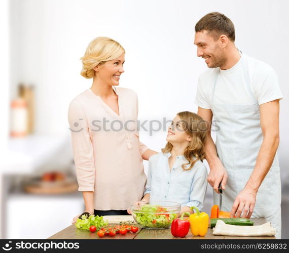 vegetarian food, culinary, happiness and people concept - happy family cooking vegetable salad for dinner and talking over home kitchen background