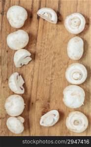Vegetarian food. Frame of fresh white mushrooms champigonons on wooden kitchen table background.