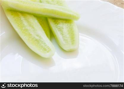 Vegetarian food. Fresh cucumber pieces on white plate. Dinner preparing.