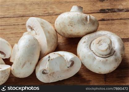 Vegetarian food. Fresh white mushrooms champigonons on wooden kitchen table.