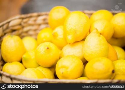 vegetarian food, fruits and citrus concept - close up of fresh ripe lemons in basket