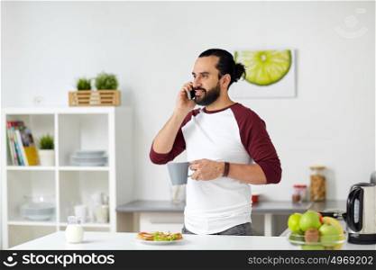 vegetarian food, healthy eating, people, technology and diet concept - man having vegetable sandwiches with coffee for breakfast and calling on smartphone at home kitchen. man calling on smartphone and eating at home