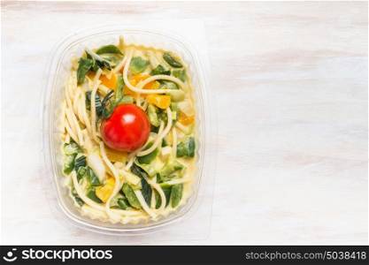 Vegetarian Noodles salad with vegetables in plastic package for healthy lunch on white wooden background, top view, place for text