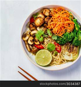 Vegetarian noodles with tofu, broccoli, mushrooms, carrot, bok choy on white stone table. Top view, flat lay, copyspace. Asian Tofu Soba Noodle Bowl. Asian Tofu Soba Noodle Bowl