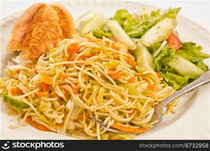 Vegetarian pasta with carrots, onions, pepper and seasonings served with salad and bread