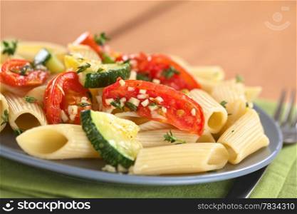 Vegetarian penne pasta dish with baked zucchini and tomato spiced with thyme and garlic (Selective Focus, Focus on the front of the tomato slice one third into the dish). Pasta with Zucchini and Tomato