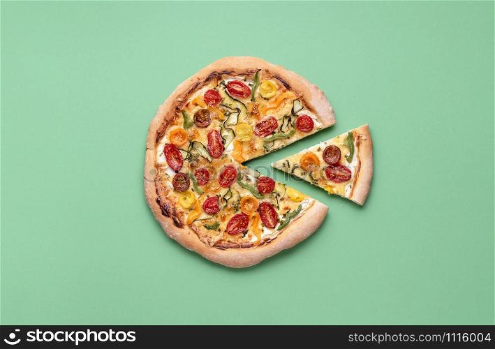 Vegetarian pizza on a green background. Pizza primavera and just one slice. Single slice of spring pizza. Italian meal. Cherry tomato pizza.
