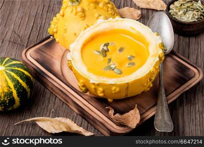 Vegetarian pumpkin cream soup with seeds in pumpkin.Seasonal autumn food.Cream soup in pumpkin. Autumn pumpkin soup