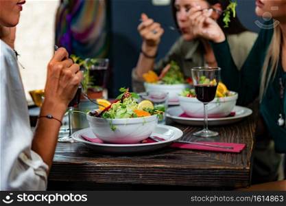 Vegetarian Restaurant. Cheerful Female Friends Enjoying Fresh Salad in Restaurant and Having Fun.