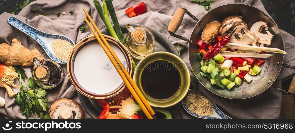 Vegetarian stir fry ingredients: chopped vegetables, spices,coconut milk, soy sauce,,wok and chopsticks, top view, banner. Asian food , Chinese or Thai cuisine concept