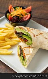 Vegetarian wrap french fries with vegetables on a white porcelain plate