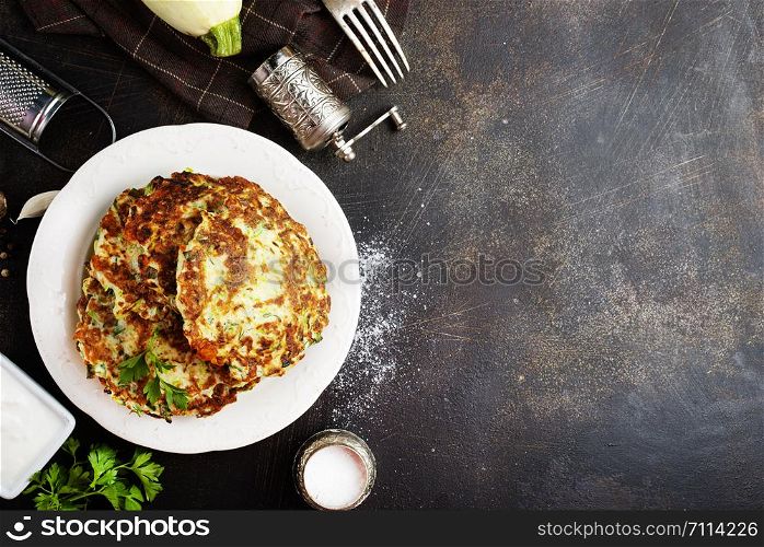 Vegetarian zucchini pancakes stack with sour cream. Vegetable pancakes