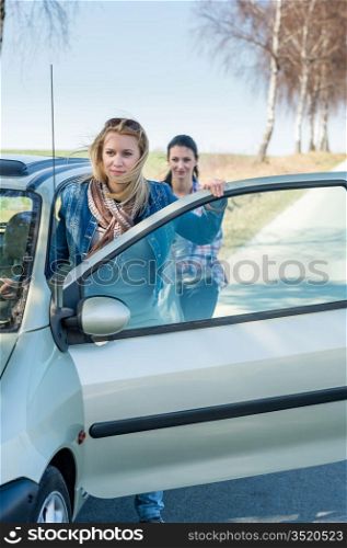Vehicle breakdown two young women pushing car down the road