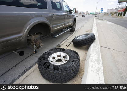 Vehicle brokendown along roadside with damaged tire needing replacement.