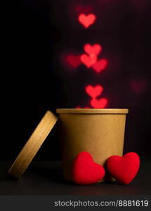 Velvet heart and paper cup of coffee on dark background with heart shaped bokeh