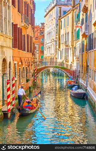 Venetian canal with gondola on sunny summer day, Venice, Italy