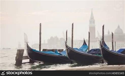 Venetian gondolas tied near the pier on San Marco square at sunrise, Venice, Italy