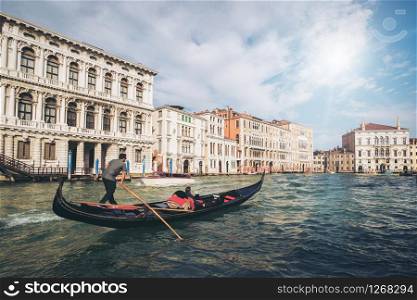 Venetian gondolier punting gondola through grand canal of Venice, Italy. Gondola is a traditional, flat-bottomed Venetian rowing boat. It is the unique transportation of Venice, Italy.