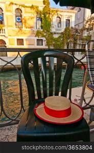 Venice Italy gondolier hat on a chair with canal on background