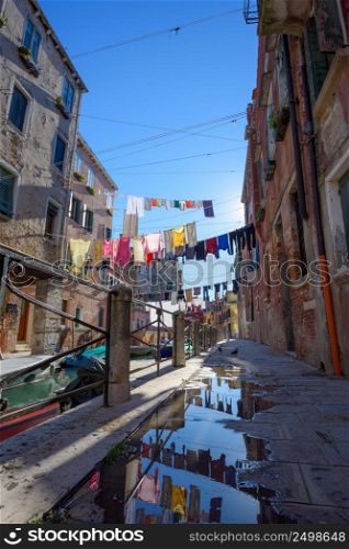 Venice Italy street with laundry washed clothes hanging out to dry on ropes between houses