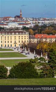 Verical cityscape with half of buildings Schonbrunn Palace in Vienna, Austria and roofs of other historical houses on a background of blue sky on an autumn day.. Cityscape with view historical buildings of Schonbrunn Palace in Vienna.