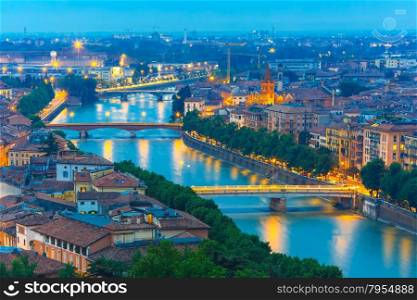 Verona skyline with river Adige and bridges at night, view from Piazzale Castel San Pietro, Italy