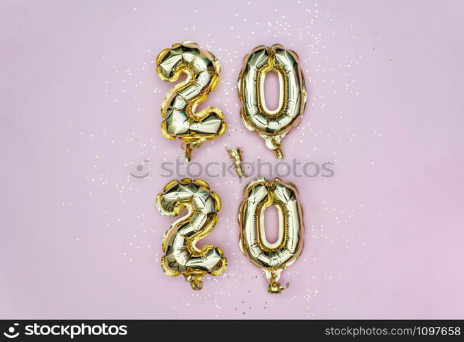 Vertical 2020 Happy New year celebration. Gold foil balloons numeral 2020 and golden stars on pastel pink backgroundl. Holiday party decoration.. Vertical 2020 Happy New year celebration. Gold foil balloons numeral 2020 and golden stars on pastel pink backgroundl.