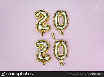 Vertical 2020 Happy New year celebration. Gold foil balloons numeral 2020 and golden stars on pastel pink backgroundl. Holiday party decoration.. Vertical 2020 Happy New year celebration. Gold foil balloons numeral 2020 and golden stars on pastel pink backgroundl.