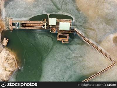 Vertical aerial photograph of the boom and suction dredger at the edge of the excavation area showing sand and the associated excavation pond, drone shot