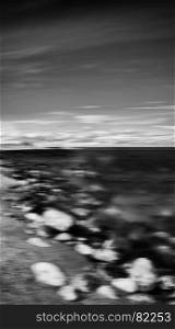 Vertical black and white dramatic stony beach motion blur abstraction background backdrop. Vertical black and white dramatic stony beach motion blur abstra