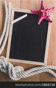 Vertical blackboard decorated by ropes and red starfish