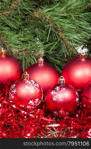 vertical Christmas still life - several red Christmas balls, tinsel on Xmas tree background
