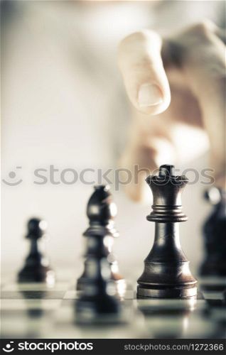 Vertical Image of a chess game with focus on the queen and a blurry hand at the background, Copy space on the left side. Concept of strategic business or risk management.. Chess Game Background