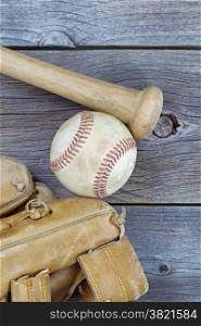 Vertical image of a partial old worn glove, bat and used baseball on rustic wood