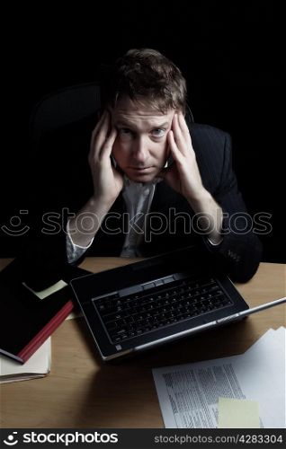 Vertical image of a tired business man working late into the night with black background