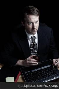 Vertical image of business man, looking at computer screen, working late with black background