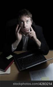 Vertical image of business man, ready to lose his temper while on his cell phone, working late with black background