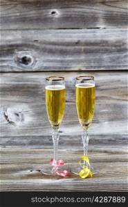 Vertical image of Golden champagne in elegant glasses on rustic wood with ribbons