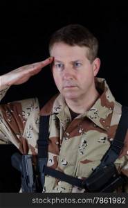Vertical image of military male soldier saluting while armed with black background.