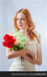 Vertical image of the redhead with bunch of flowers in studio on white