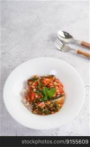 Vertical image, Selective focus appetizers with sardine in tomato sauce and spicy mixed with herb in white plate, blurred spoon and fork, copy space