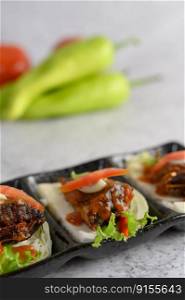 Vertical image, Selective focus appetizers with spicy sardine mixed with herb placed on cabbage in ceramic tray, blurred green peppers and tomato, copy space