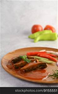 Vertical Image, Selective focus canned sardine with tomato sauce pepermint on top and cooking ingredient was arrangement in wooden tray, blurred green chili and tomato, copy space