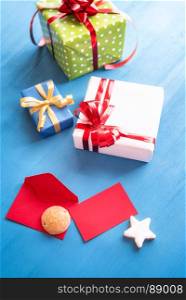 Vertical image with a bunch of multicolored presents, a red opened envelope with an empty card, gingerbread and delicious star shaped cookies.